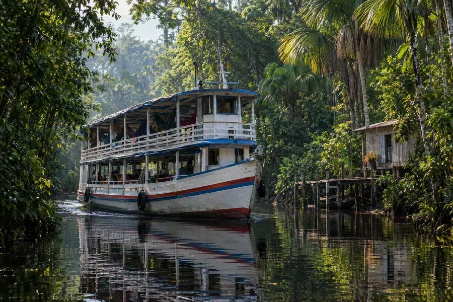 Barco regional num rio estreito cercado de floresta