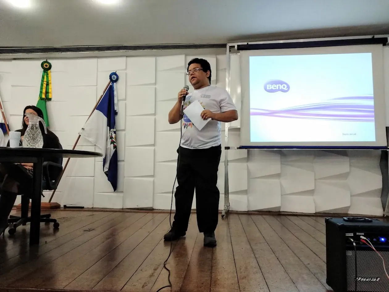 Alexander falando no lançamento do aplicativo Um Novo Caminho, com um slide projetado ao fundo, em 2018