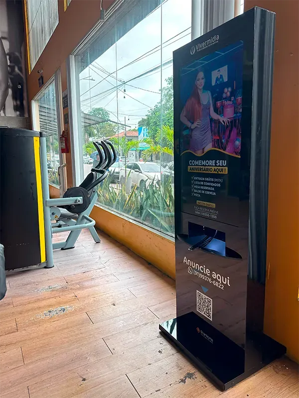 Totem de mídia digital Vivermídia instalado junto à janela de uma academia